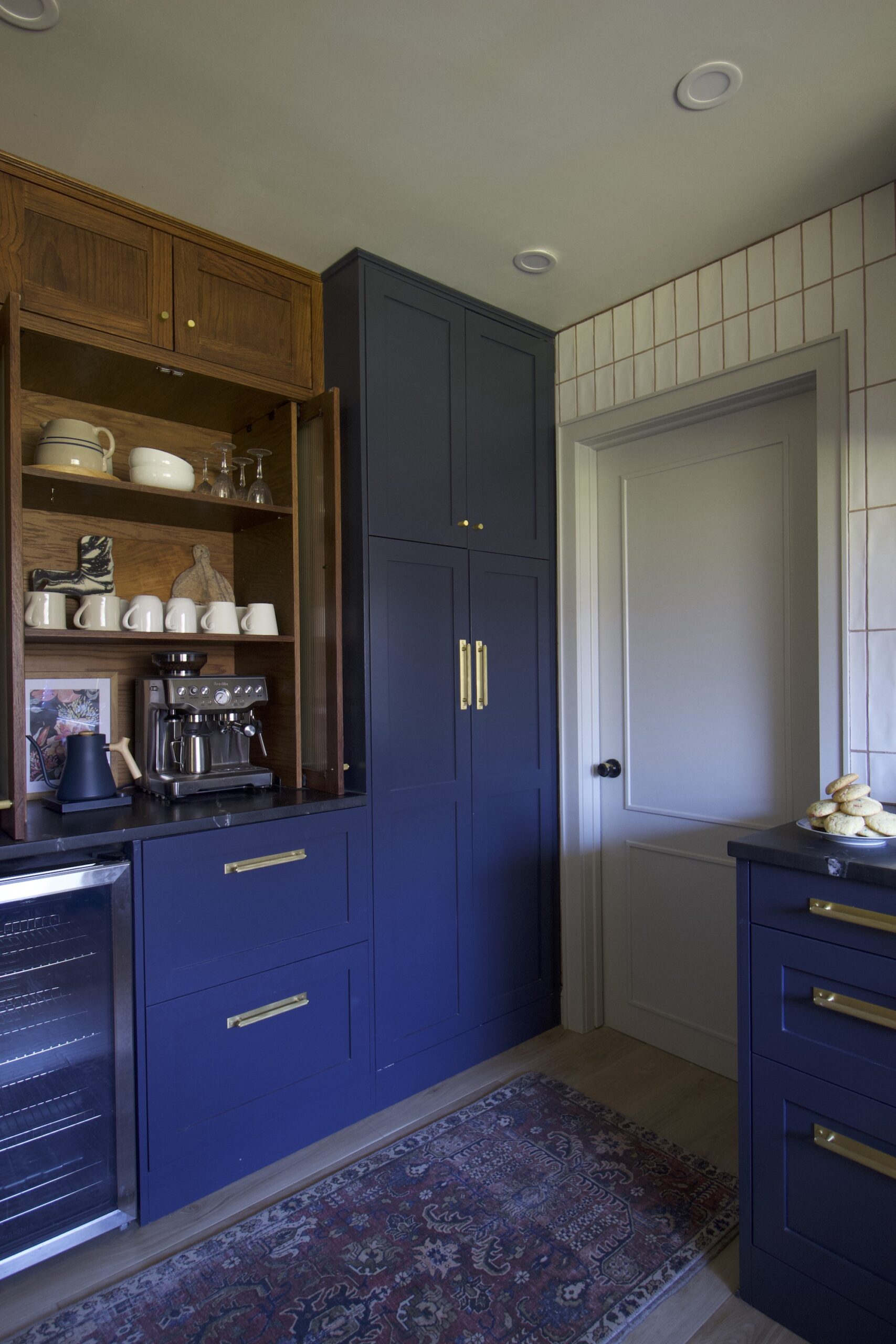 moody kitchen with navy cabinets and black countertop and medium wood stained cabinets